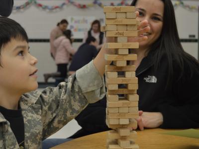 Boy pulls Jenga piece while mother looks on.